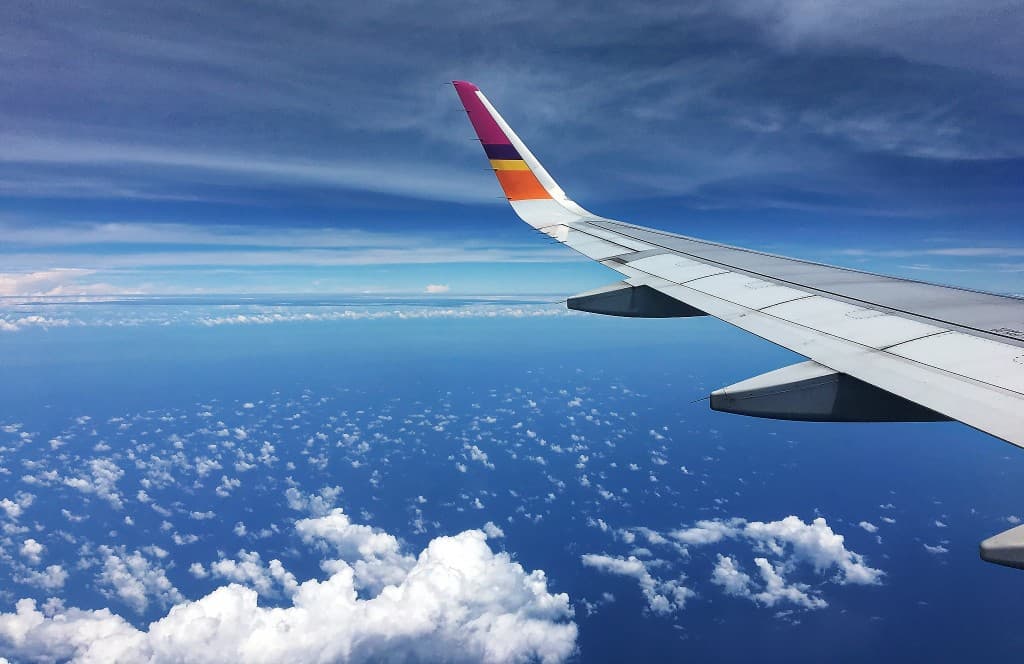 Blick aus einem Flugzeugfenster über den Wolken